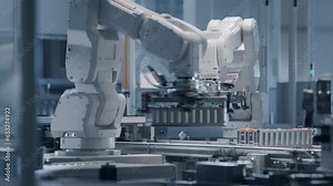 White Robotic Arms Transporting Automotive Battery Module onto Conveyor Belt. Electric Car Battery Pack Production Process. Bright Automated Factory. Lithium-ion Battery Cell Manufacturing Line.