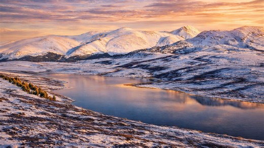 The frozen lake surrounded by snow-covered Altai Mountains