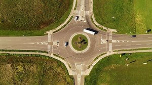Many cars on road circular intersection roundabout, top view drone pov