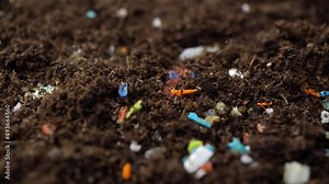 Microplastics inside the soil. Concept of global warming and climate change. Non-recyclable plastic pollution in the soil. Person examining the micro plastics with a tweezers.