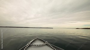 Speed. Pov. Navigating the lake. View of the bow of the inflatable boat across the water. The shoreline in the horizon.