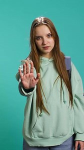 Vertical Assertive young woman doing stop hand gesture and talking. Annoyed girl doing firm halt sign gesturing, wishing to end concept, isolated over blue studio background, camera B