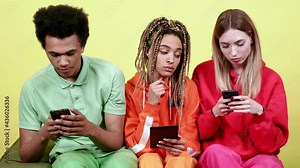 Young people sitting together watching each other using smartphones