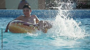 Entertaining boy splattering water with his feet in a wading pool in slow motion