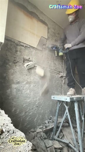 Workers use electric picks to remove old tiles from the wall