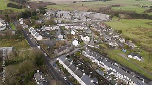 High-elevation aerial of Princetown in Dartmoor, revealing residential layouts, moorland surroundings, and the iconic circular HM Prison Dartmoor structure at the village’s edge