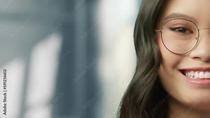 Eyes of wonderful asian young woman in modern eyeglasses. Beautiful face pretty chinese girl posing indoors on blurred grey neutral background. Ethnicity concept close-up portrait, real people 4K shot