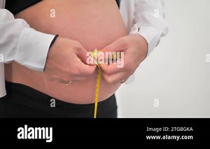 Prenatal state of the body. Close-up shot of a pregnant woman measuring the size of her belly with a tape, white studio background Stock Video Footage - Alamy