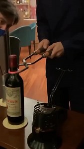 A 1961 Pétrus opened using the "Portuguese method," a technique for bottles with delicate corks. Heated "Port Tongs" are clamped to the neck to transfer heat. A splash of cold water causes the glass to crack cleanly, allowing access to the wine. 🎥@luxandgo . . . . . #thewinecrate #vintagewine #finewine #winelovers #pétrus #portuguesemethod #wineart #sommelierlife #oldwine #rarewines #porttongs #petrus #winecraft #winetradition #decanting #wineexperience #luxurywine | The Wine Crate