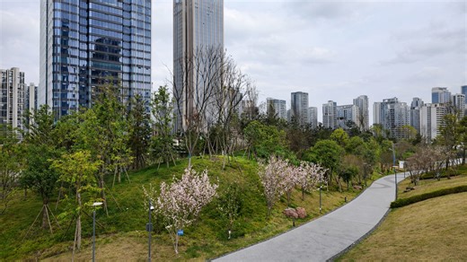 Urban park pathway extends through trees and hills in China