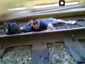 Guy stuck under moving train escapes between its rails