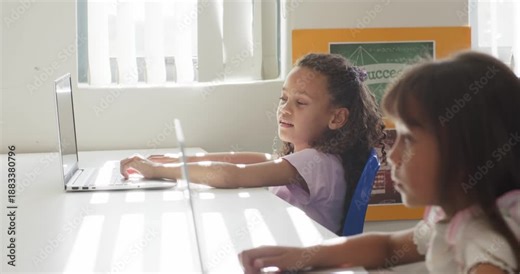 African American school-age girls typing and reaching while camera panning doing work on laptops