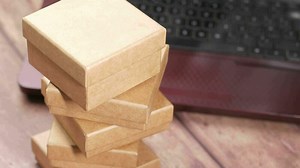 Stack of cardboard parcels and laptop on table