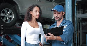 Mechanic explain the cost of service to female client, Automobile service center worker shaking hands with client after car servicing.
