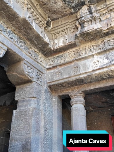 Ajanta Caves – Exterior Entrance Detail Carved directly into the basalt cliffs of Maharashtra, the entrance to one of the rock-cut caves at Ajanta reflects the architectural language of structural timber buildings translated into stone. The façade is framed by solid pillars with simple bases and capitals, supporting a carved architrave and decorative friezes above. Along the lintel and cornice, miniature sculpted panels depict figures and narrative scenes, while medallions containing relief carv