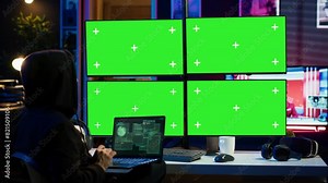 Man writing code on laptop in front of isolated screen PC monitors, trying to get past security systems. Hacker using chroma key computer and notebook to make scripts that can hack devices, camera A
