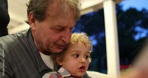 Grandson and grandfather together. Grand-pa telling story to toddler