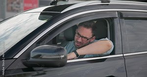 Sad angry man sitting in a car in a traffic jam and gesticulating angrily in impatience and irritation