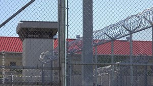 IOWA - 6.28.2024 - Exteriors of the Iowa State Penitentiary seen through layers of barbed wire fence.