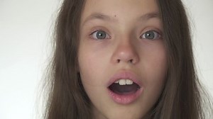Beautiful happy teenage girl is surprised and laughing close-up on a white background stock footage video