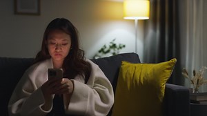 Free stock video - Woman sitting on a couch at night using her phone