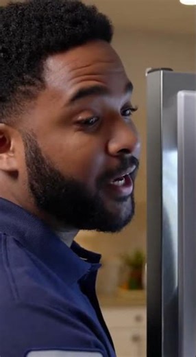 Technician adjusting fridge temperature control panel, explaining