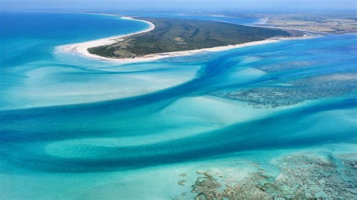 A sand island surrounded by moving tides