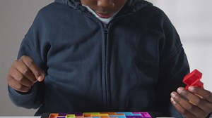 Free stock video - Close up of boy on asd spectrum solving shape puzzle on white background 1