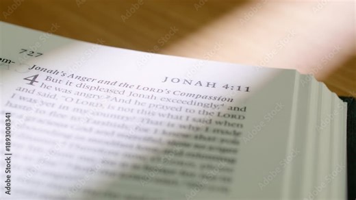 Bible Obadiah and Jonah pages turn during a close up study of holy scripture. Witness the transition from the prophecy of Obadiah to the narrative of Jonah in a modern religious book for study.