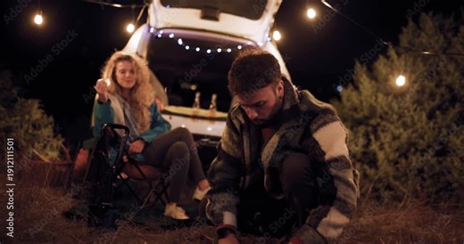 Camping under stars with friends, setting up fire at night in nature, enjoying outdoor moments together by vehicle in remote area