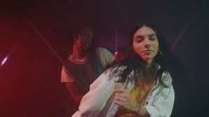 Dancers performing a modern hip hop dance in a black studio with colored lights and effects. Young multiethnic crew training a choreography for the show.