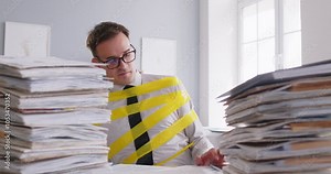 Stressed businessman screaming in frustration while working with piles of documents in the office. Overwork and fatigue, he faces numerous business problems, troubles and struggles to manage workload.