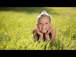 Little girl at sunset on the grass and smiling at camera