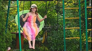 Cute teen girl in summer dress swinging on a swing. joy, fun, happiness