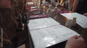 Push in on plastic menu at a table of friends at a restaurant
