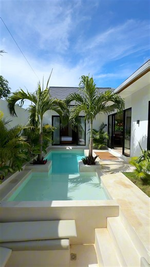 Hop in, this villa tour is about to get dreamy! With a sunken lounge and jacuzzi, it’s basically a VIP section for chilling. The floor-to-ceiling glass doors blur the line between indoors and Bali’s tropical magic, flooding the space with sunshine and poolside vibes. Speaking of the pool, it’s got depths for both lazy lounging and actual swimming (if you’re feeling ambitious). Wrapped in lush greenery and sleek natural finishes, this place screams luxury with a side of barefoot comfort. The perf