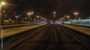 Railway tracks view from moving train leaving the station at night