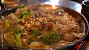 A plate filled with stir-fried broccoli and savory pad see ew noodles, A sizzling hot plate of pad see ew noodles stir-fried with tender slices of beef and crispy broccoli
