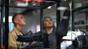 Couple looking at the footwear sold in the store. Lady takes a shoe from a shell and shows it to her boyfriend. Blurred backdrop.