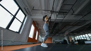 Young beautiful female boxer jumping on the skipping rope training in fitness gym. Slow-motion wide shot.