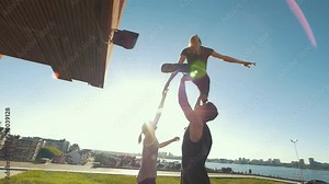 Team of cheerleaders practice outdoors at summer day - muscular man young woman support the girl in air