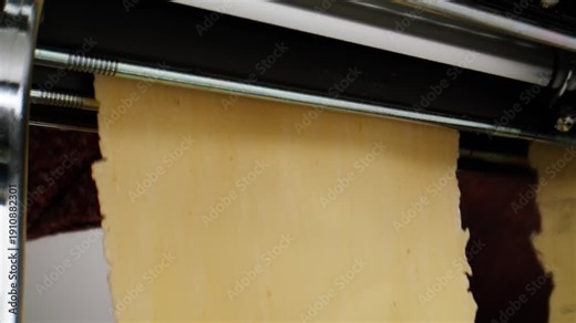 Woman using pasta machine to make fresh pasta dough in the kitchen, cooking in italian restaurant, making noodles.