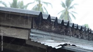 Close up of the eaves with water drop in heavy rainy weather. Raindrop on roof of rural house. Relaxation in cold and raining day.