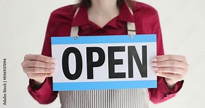 Waitress holds OPEN sign and stands ready to greet patrons