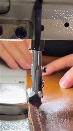 stitching a long straight line onto a brown leather material using a heavy duty sewing machine tool.