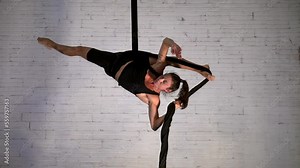 Display of strength and flexibility performed by a slim and fit female acrobat performing aerial acrobatics