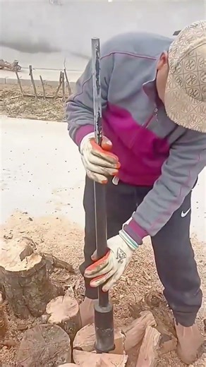 Worker splitting firewood using manual log splitter outdoors safely