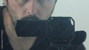 Man behind camera directing and recording scene, video production enthusiast using digital camcorder to capture footage.