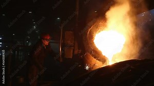 Discharge molten steel pouring from ladle Worker is turning hoop wheel to discharge molten steel from ladle into the mold for casting.