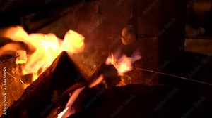 This video shows delicious marshmallows roasting over fire for campers s'mores, against a dark night sky.